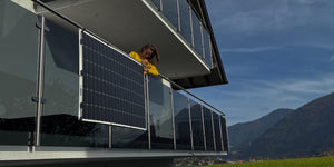 Bild von einem mehrstöckiges haus. Focusiert ist es auf den Balkonen auf dessen ein Popper Power Plug and Play Balkonkraftwerk instaliert ist. Ein glückliches Mädchen steht auf dem Balkon hinter dem Solarpannel.